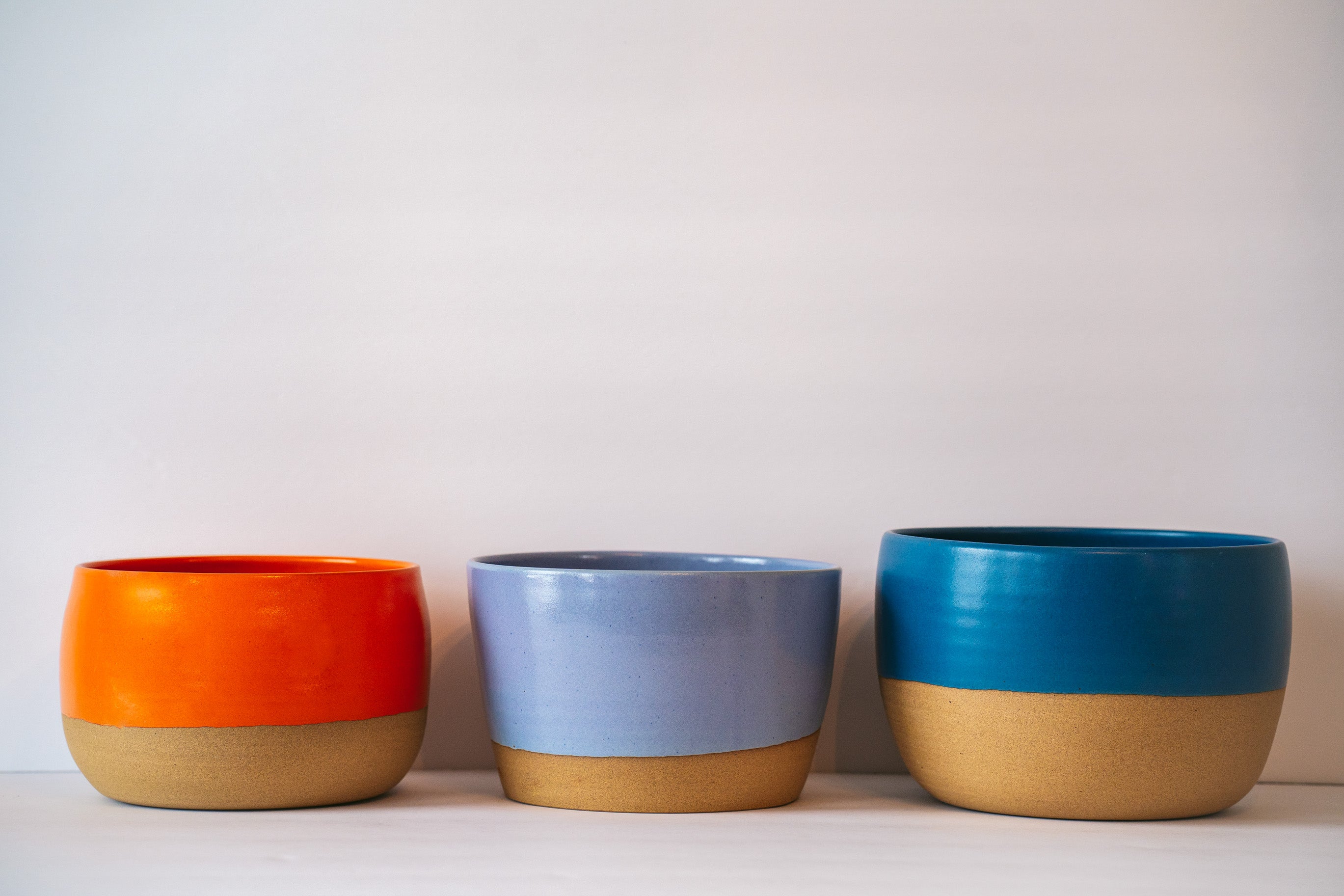 Three different wide table planter in orange, lavender and dark blue